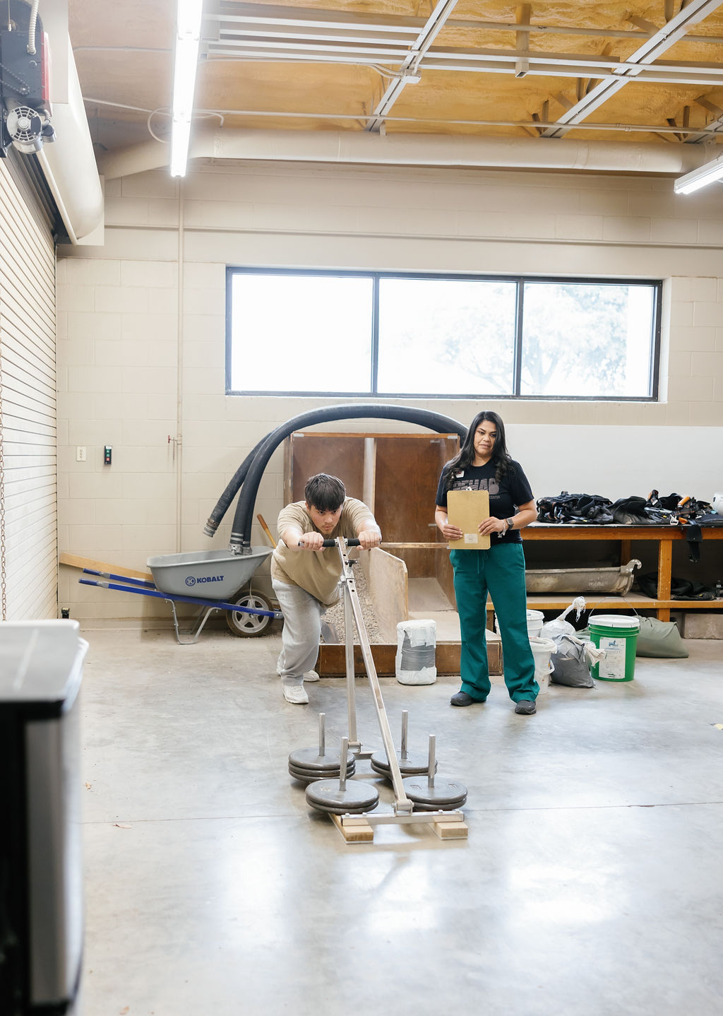 Patient performing functional weight training by pushing weights at West Texas Rehab to test strength and endurance.