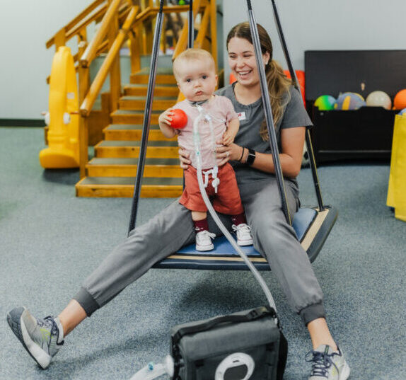 Pediatric physical therapy patient playing on a swing at West Texas Rehab to improve core mobility and balance.