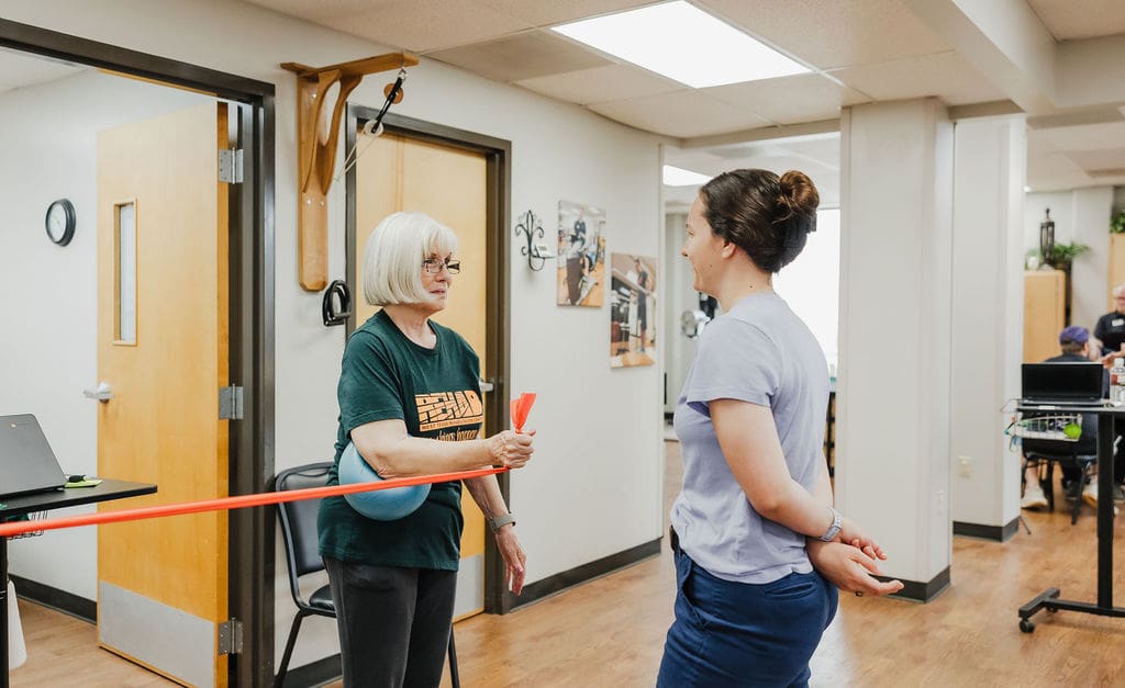 Adult therapy patient using a ball and resistance band during rehabilitation exercises at West Texas Rehab.