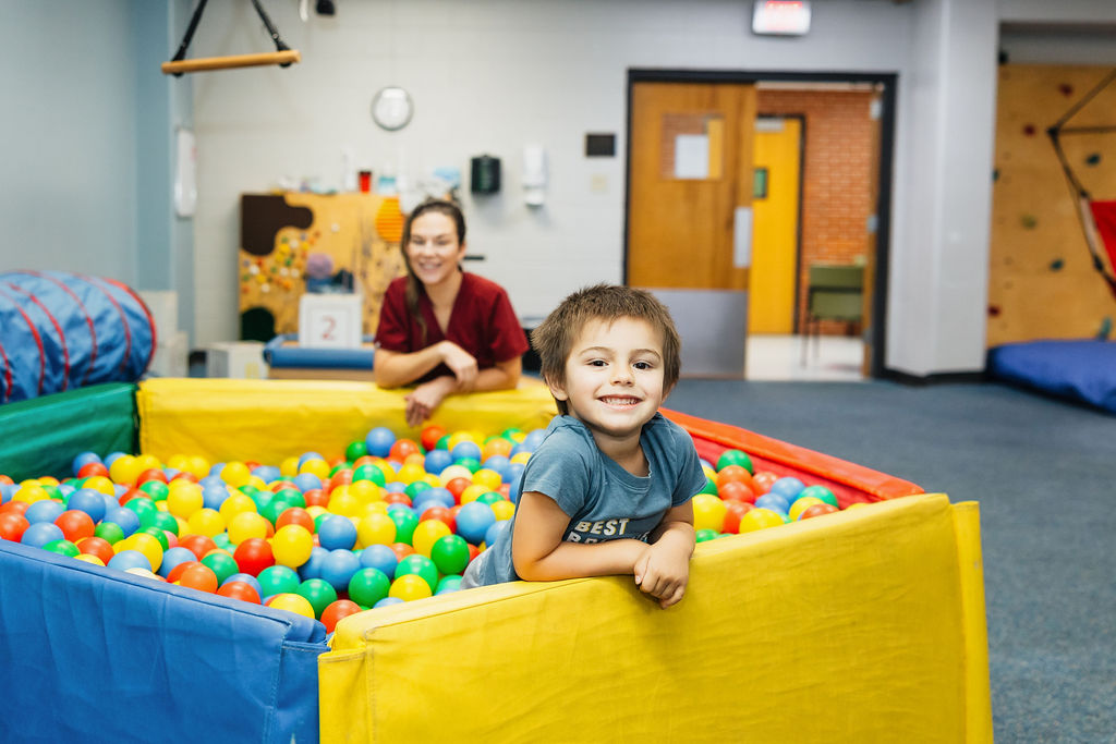 Pediatric physical therapy patient playing in a ball pit at West Texas Rehab to improve motor skills and coordination.