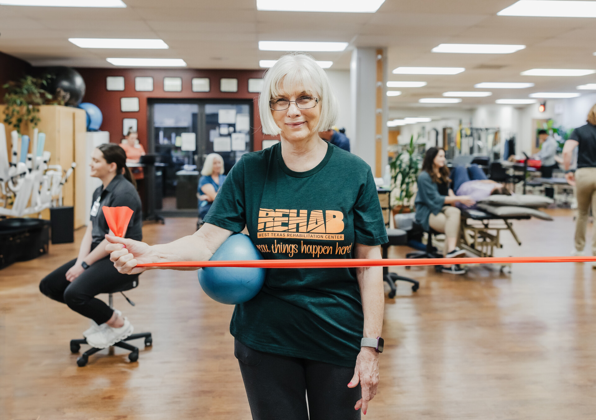 Patient at West Texas Rehab using resistance bands and a therapy ball to improve strength and mobility.